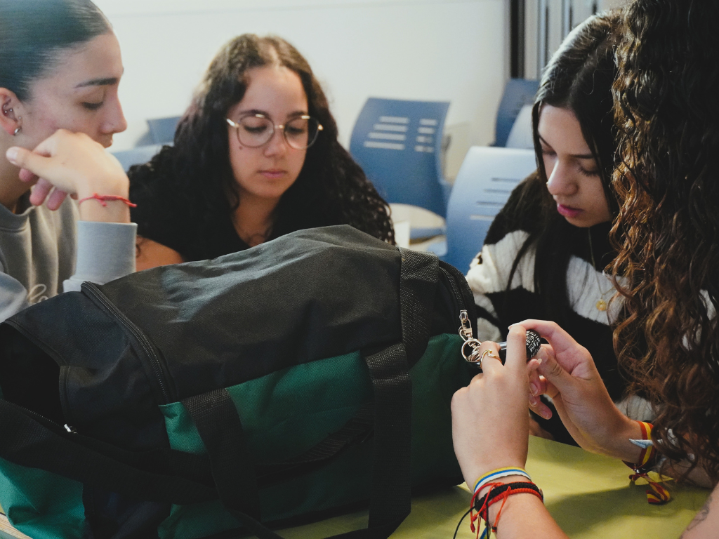 El equipo verde trabaja en equipo para abrir su maleta y avanzar en `El Viaje`, el Escape Room de Cesal sobre la realidad migratoria. / Foto: Cesal