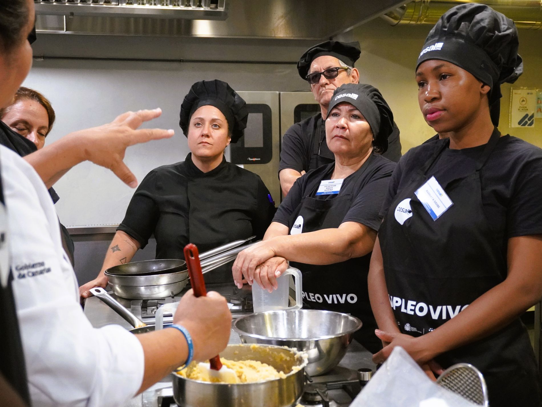 Diana Marcelino comparte trucos para preparar churros de gofio bajo la atenta mirada de los participantes y de Patricia, docente de la formaci�n de Ayudante de Cocina de Cesal. / Foto: Cesal