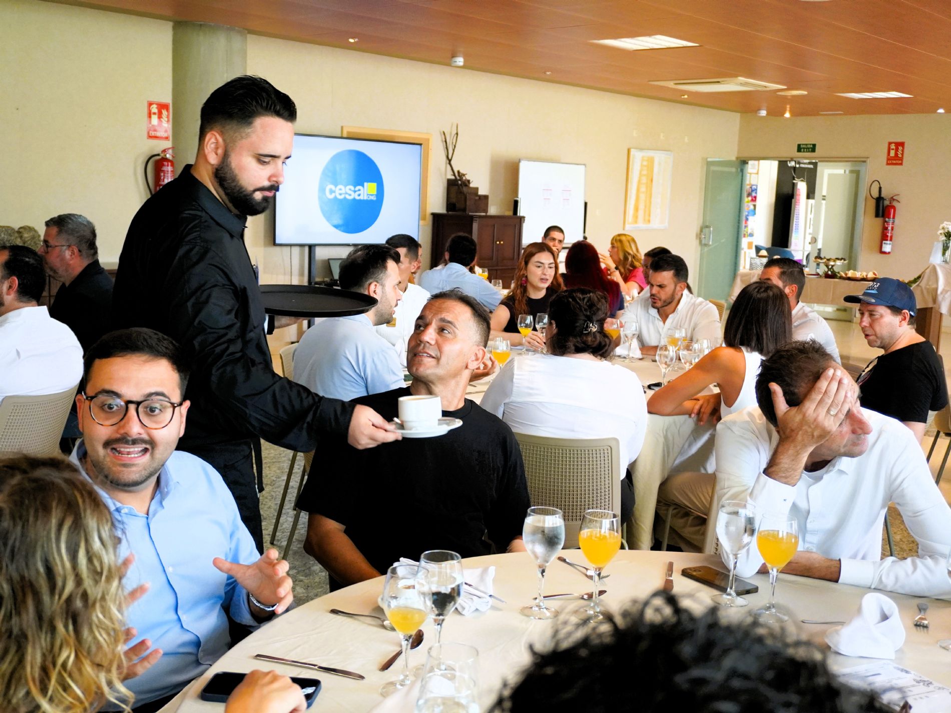 Un participante de Ayudante de Sala-Barista de Empleo Vivo atiende a los invitados durante el servicio de mesa en el CDTCA de Adeje. / Foto: Cesal